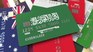 Many credit cards with different flags, emphasised bank card with flag of Saudi Arabia